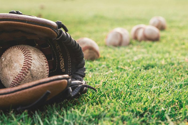 a close up of a baseball in a baseball glove on grass