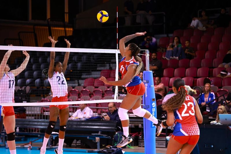 a female volleyball player about to spike a volleyball over a volleyball net