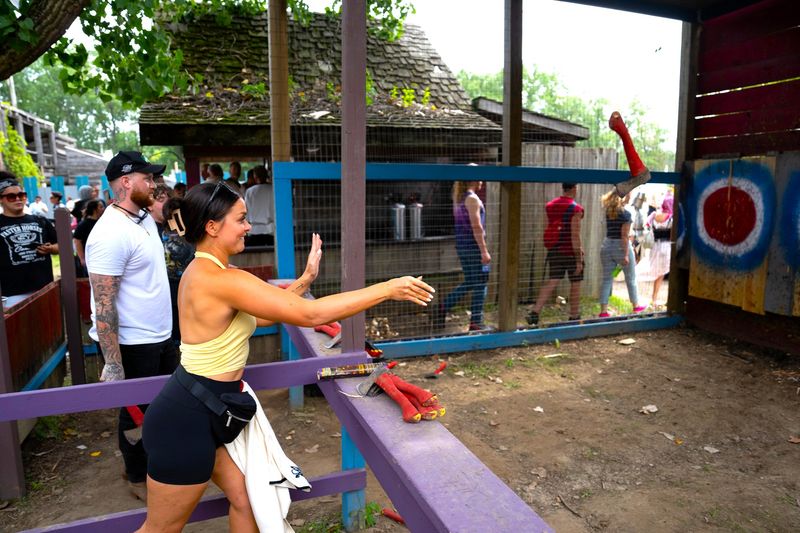 a couple throwing small axes at axe throwing targets