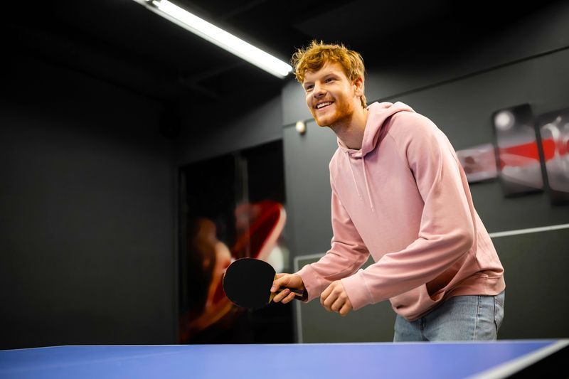 an adult male playing ping pong waiting to return a serve