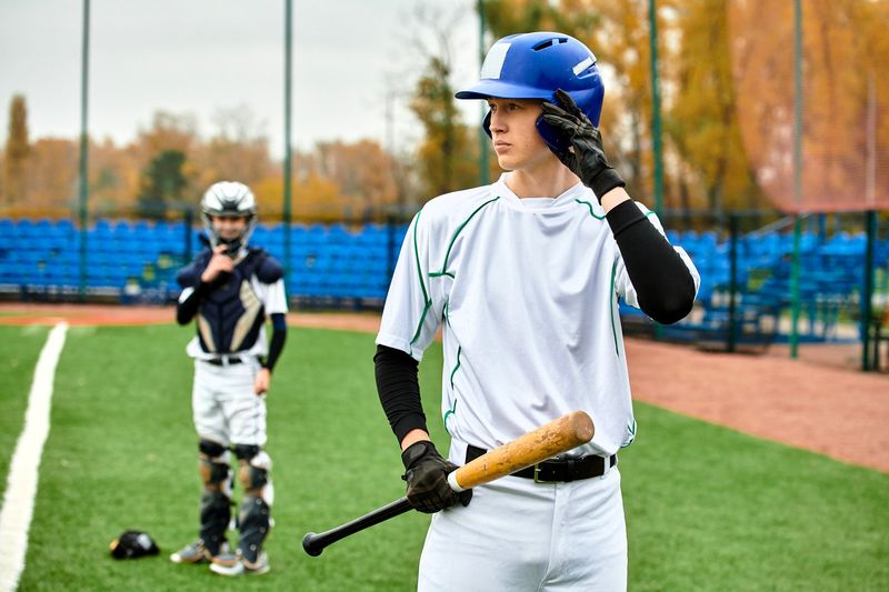 a teen baseball player touching his baseball helmet