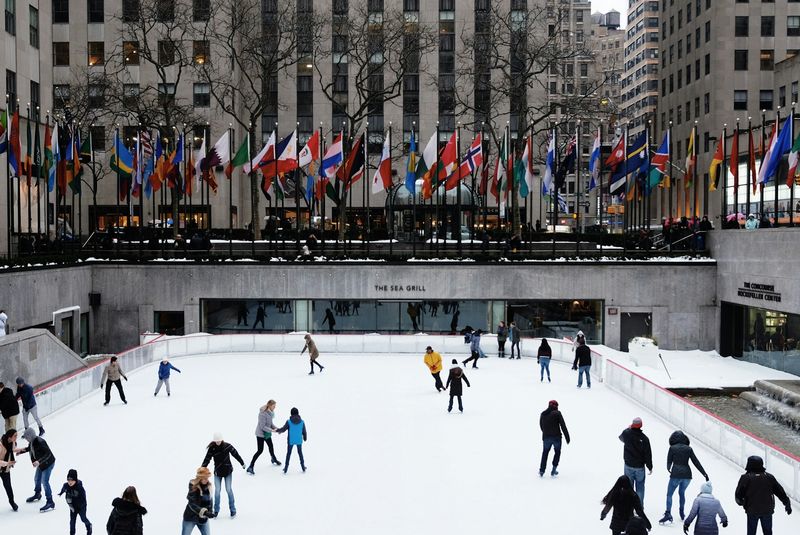 an outdoor ice rink in new york with multiple people skating on the ice