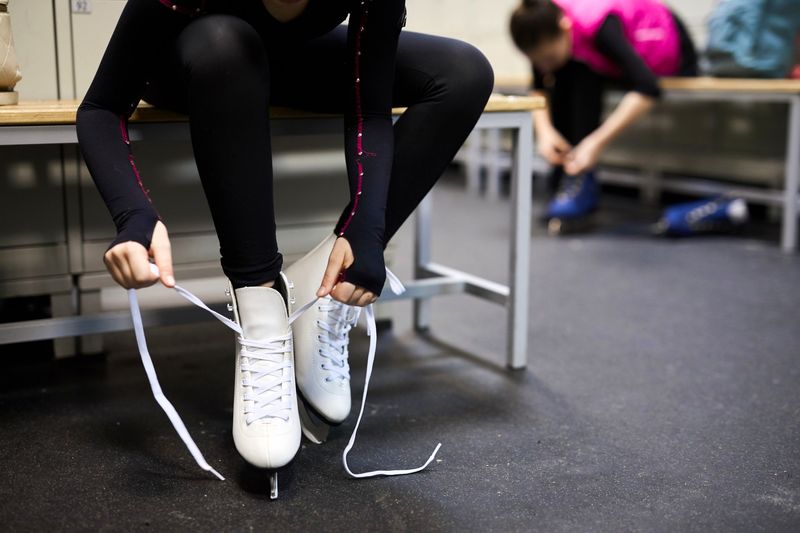 a young girl tying laces on her ice skates