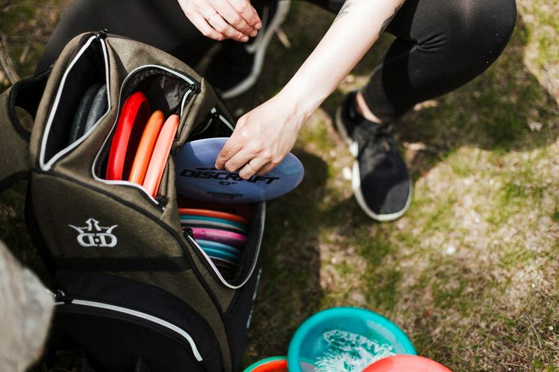 a man reaching into a disc gold bag and pulling out a blue disc