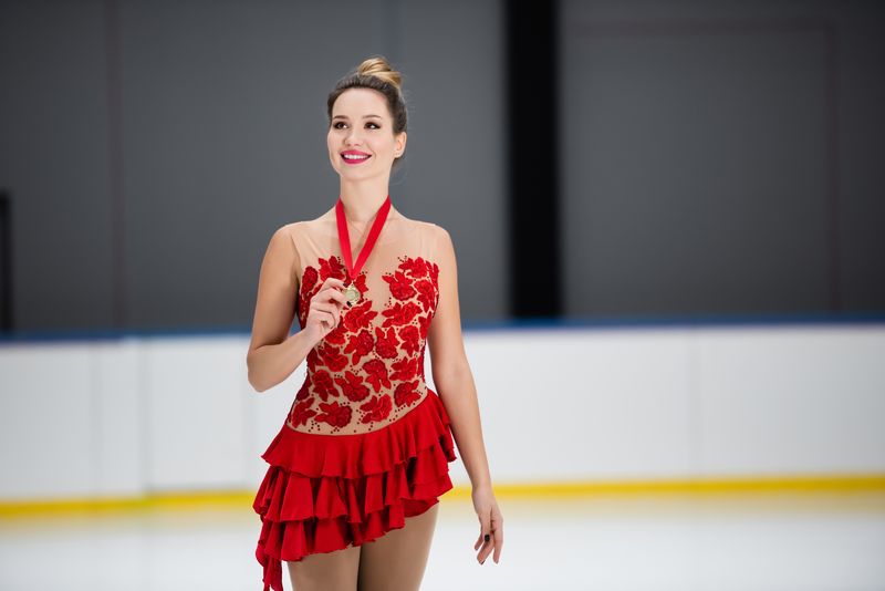 a female figure skater wearing a red dress holding a medal
