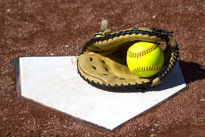a softball gloves and softball on top of a base