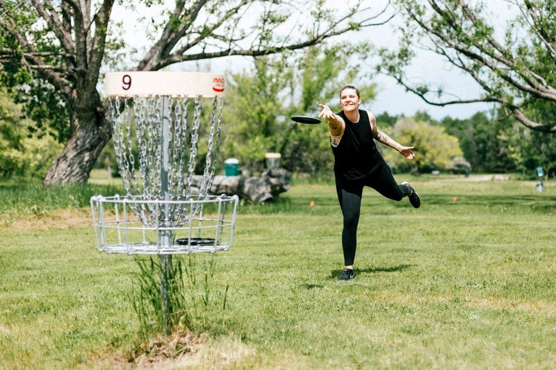 an adult female playing disc golf on grass