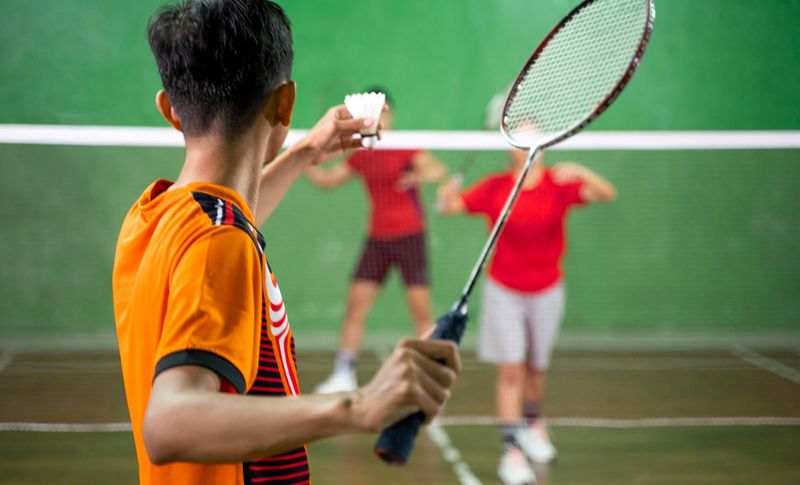a badminton player about to serve a shuttlecock