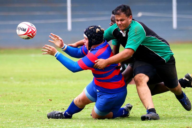 a rugby player tackling a rugby player receiving a pass