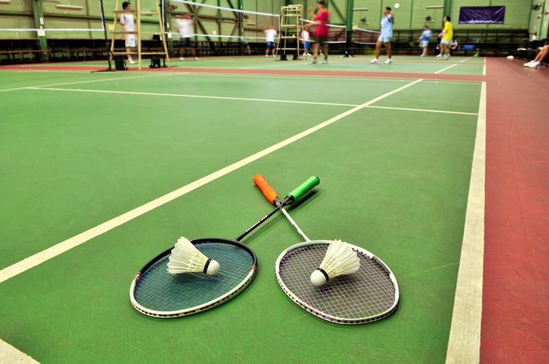 a close up of two badminton rackets and shuttlecocks lying on a green badminton court