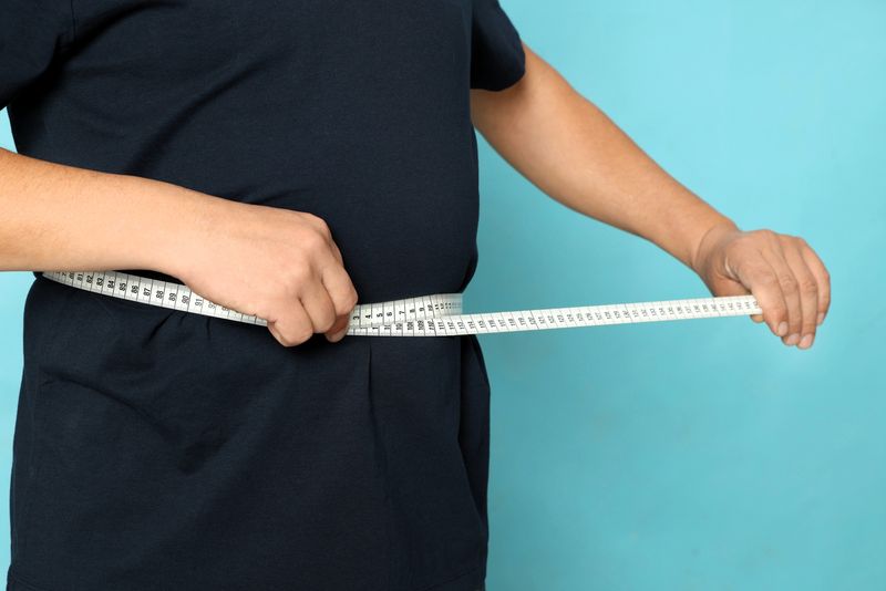 an adult male using a soft measuring tape to measure his torso width