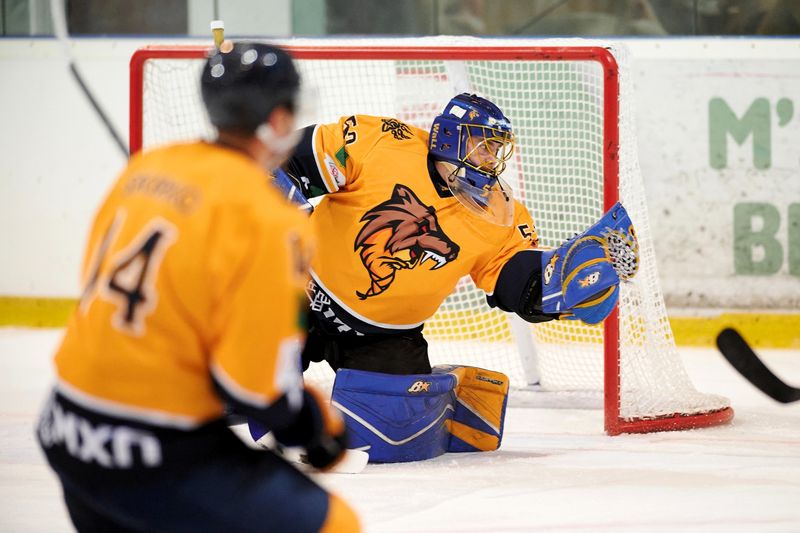 a hockey goalie catching a hockey puck in his left hand glove