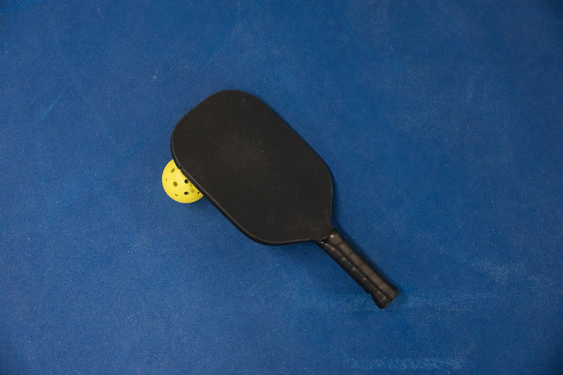 a black pickleball paddle and pickleball
