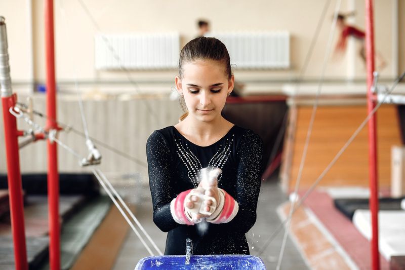 a youth female gymnast putting chalk on her hands
