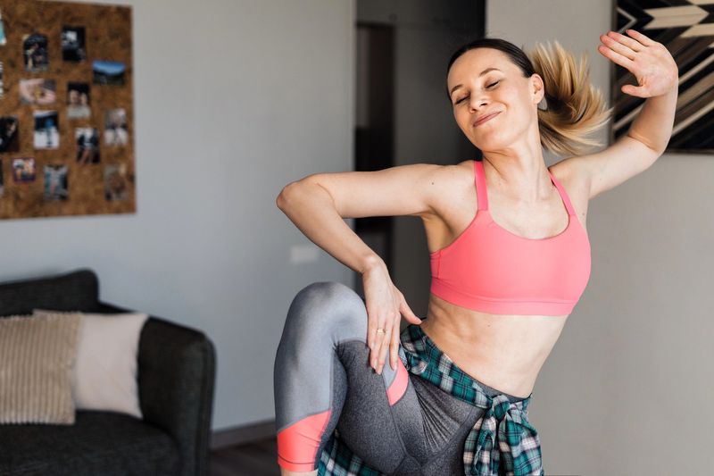 an adult woman practicing cheer poses in her living room
