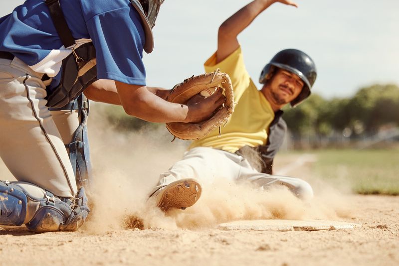 a male baseball player sliding in dirt to a base