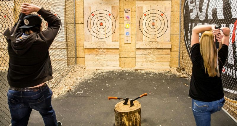 a man and woman about to throw axes at seperate targets