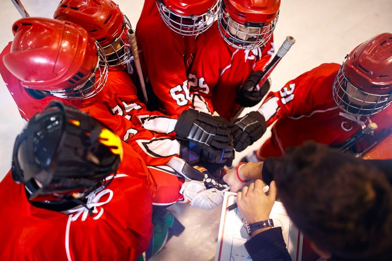 a hockey team in a huddle wearing red jerseys