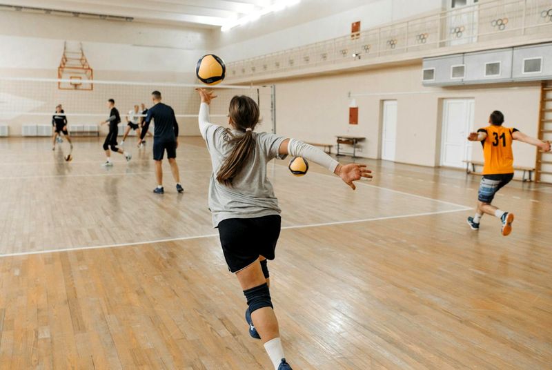 a volleyball player about to serve during an indoor volleyball game