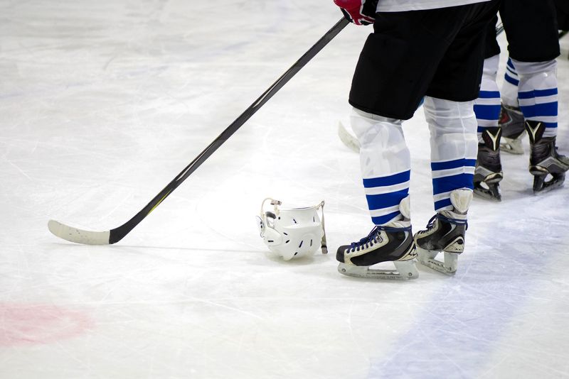 an ice hockey player standing on an ice rink next to a helmet on the ice