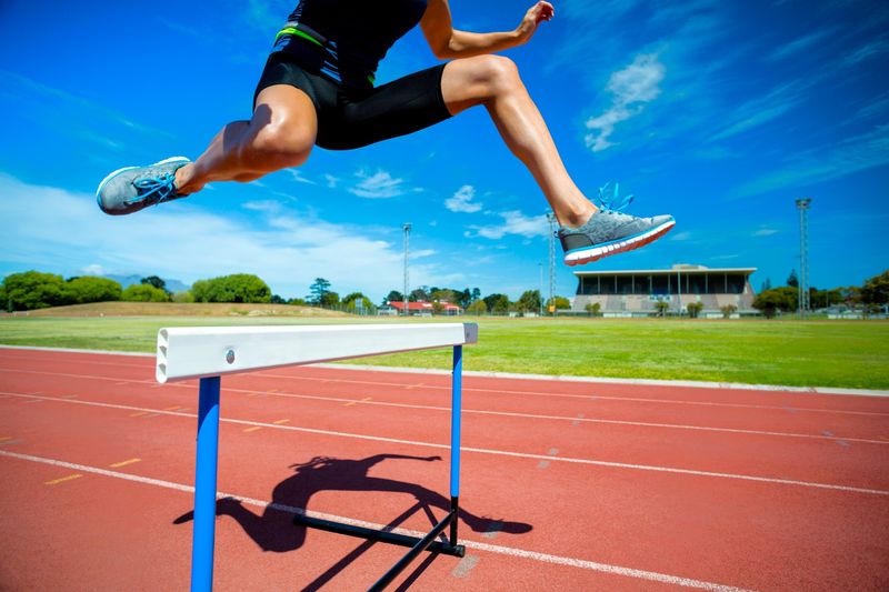 a track and field athlete jumping over a hurdle