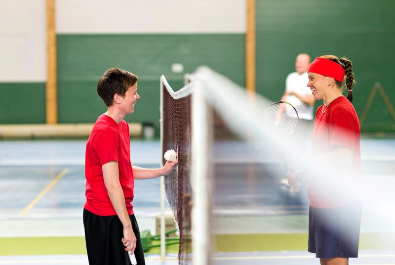 two badminton players smiling at each other between the badminton net