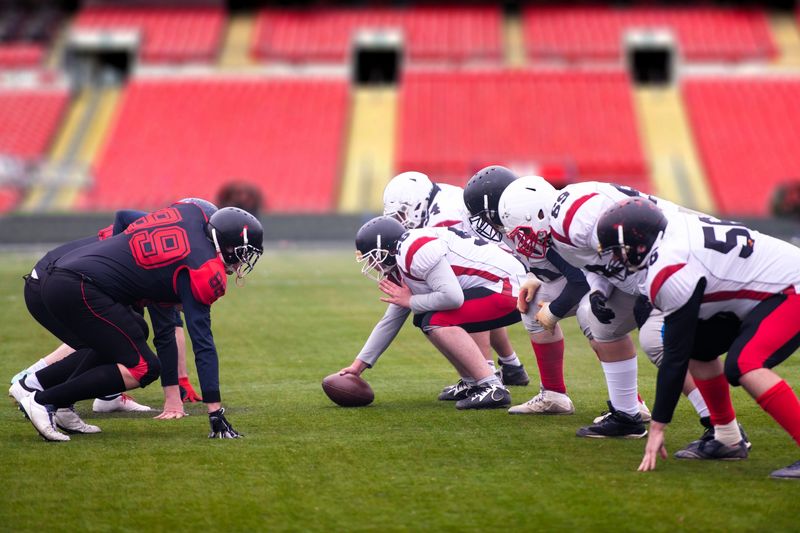two opposing football teams about to hike a football