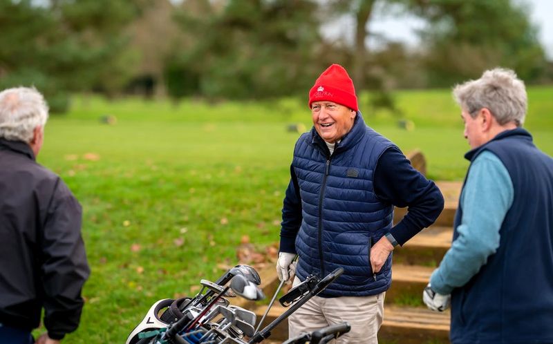 three men in a conversation preparing to play golf in cold weather clothing