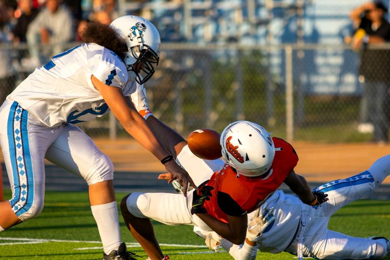 competing football players trying to catch a football