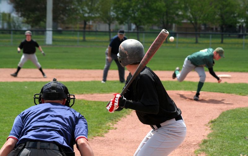 a youth baseball pitcher pitching the baseball to a batter