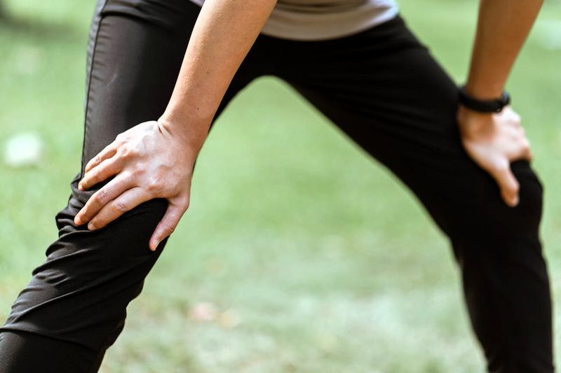 a female with her hands on her knees wearing nylon track pants