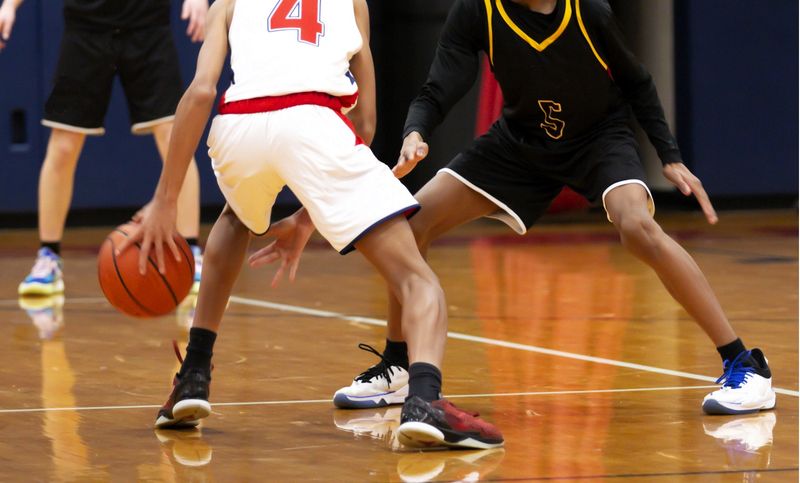 competing basketball players playing basketball on an indoor basketball court