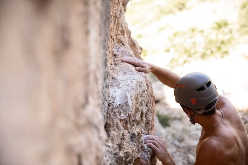 an adult male outdoor rock climbing wearing a helmet
