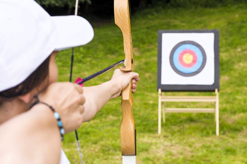 a female archer about to shoot an arrow at target