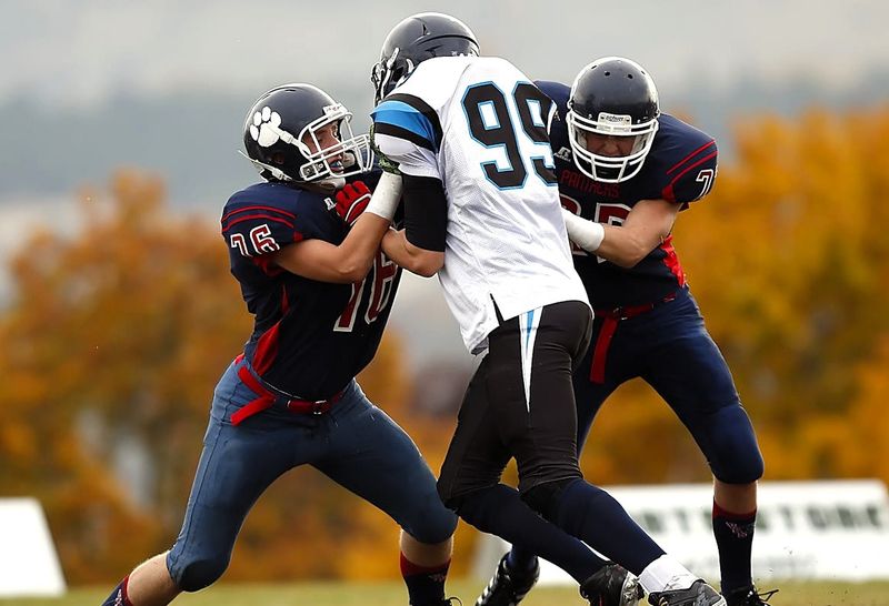 two football players tackling another football player