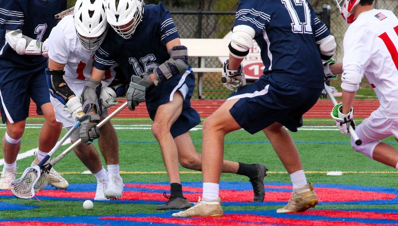 two competing lacrosse teams battling for the lacrosse ball