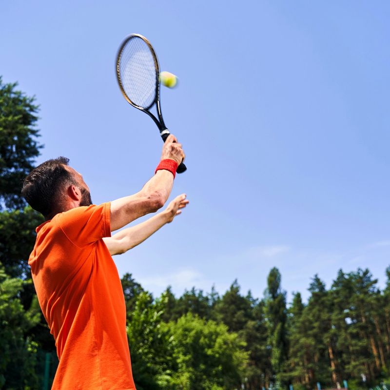 an adult male serving a tennis ball