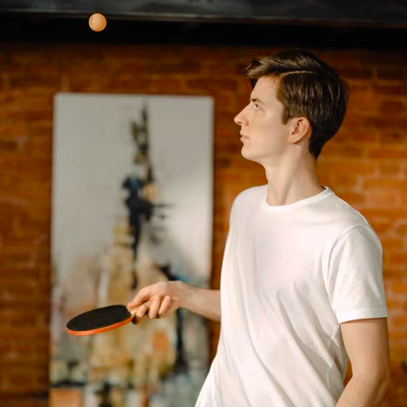 a young man practicing ping pong solo in a bedroom