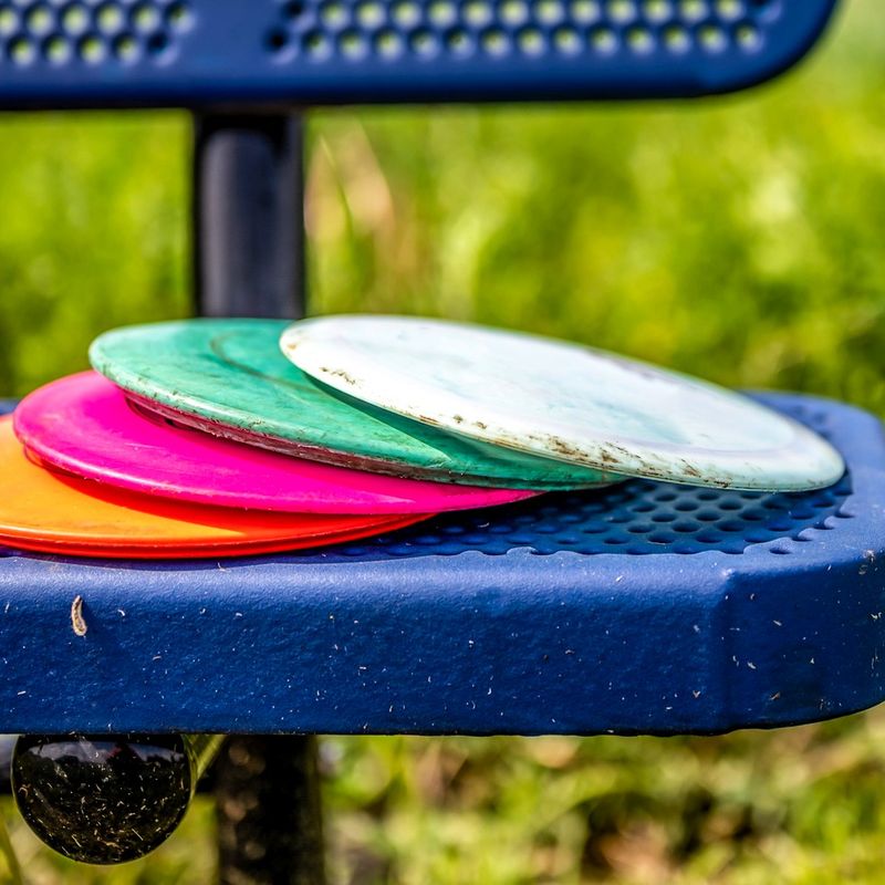 a stack of disc golf discs sitting on a blue bench seat