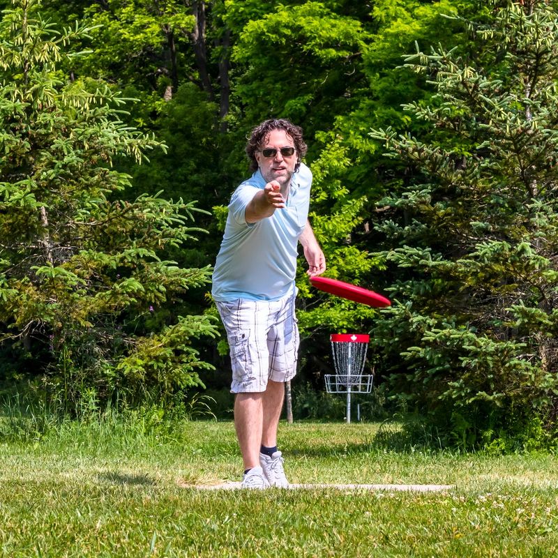 a male disc golf player throwing a disc golf disc