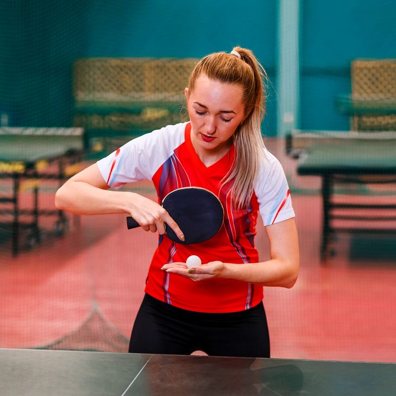 a youth female ping pong player holding a paddle using a Shakehold grip