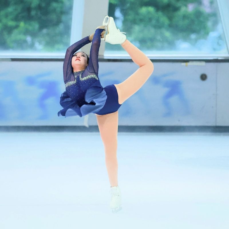a female figure skater doing a pose on an ice rink