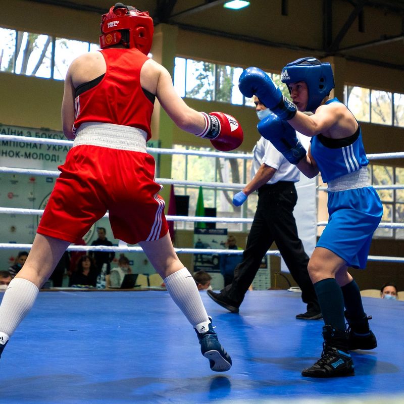 two boxers boxing in a ring with referee