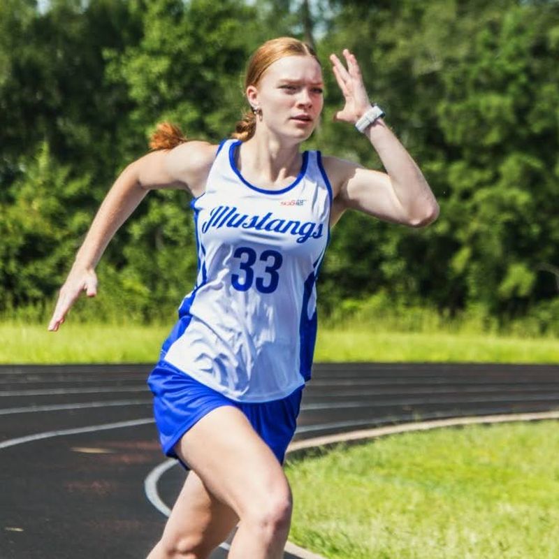 a female track and field athlete running an outdoor running track