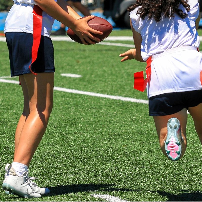 a flag football quarterback handing the football to a team member