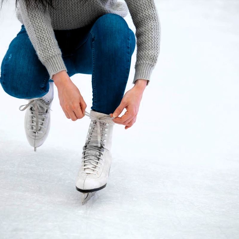 an adult female tying laces on an ice skate