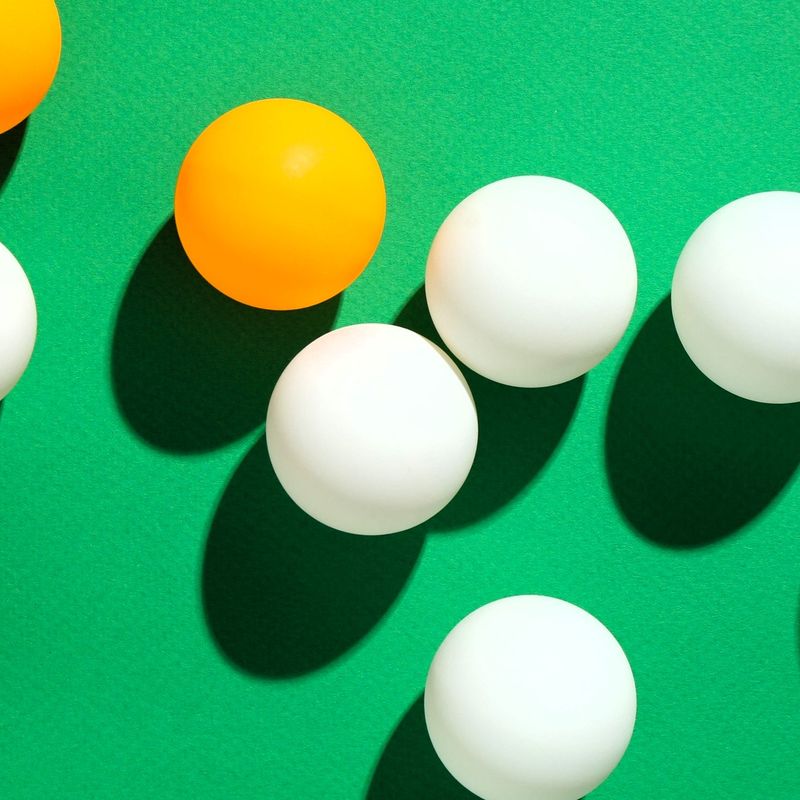 multiple orange and white ping pong balls on a green table