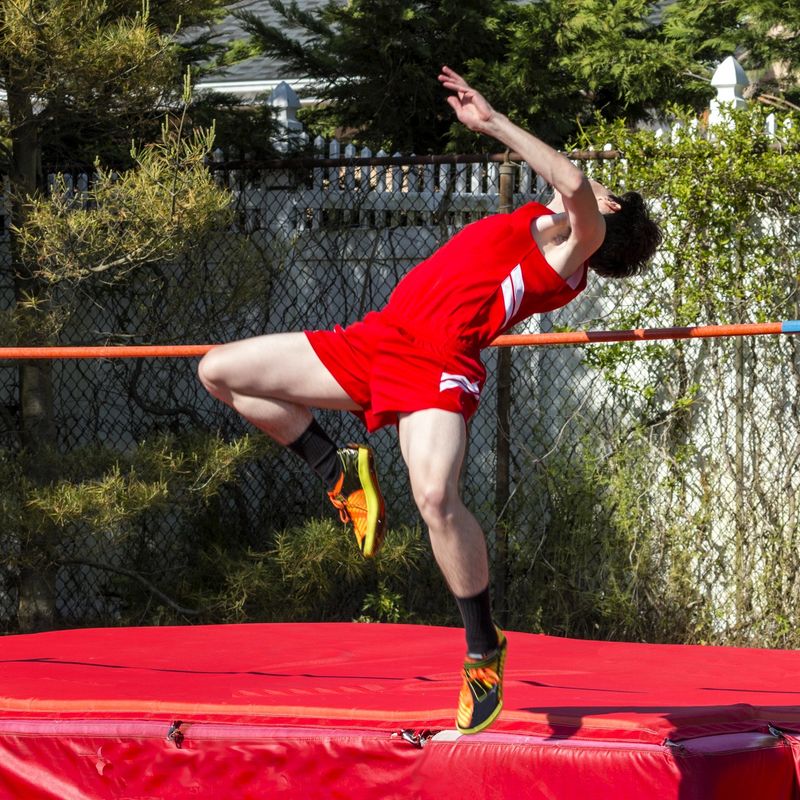 a male high jump athlete performing a high jump