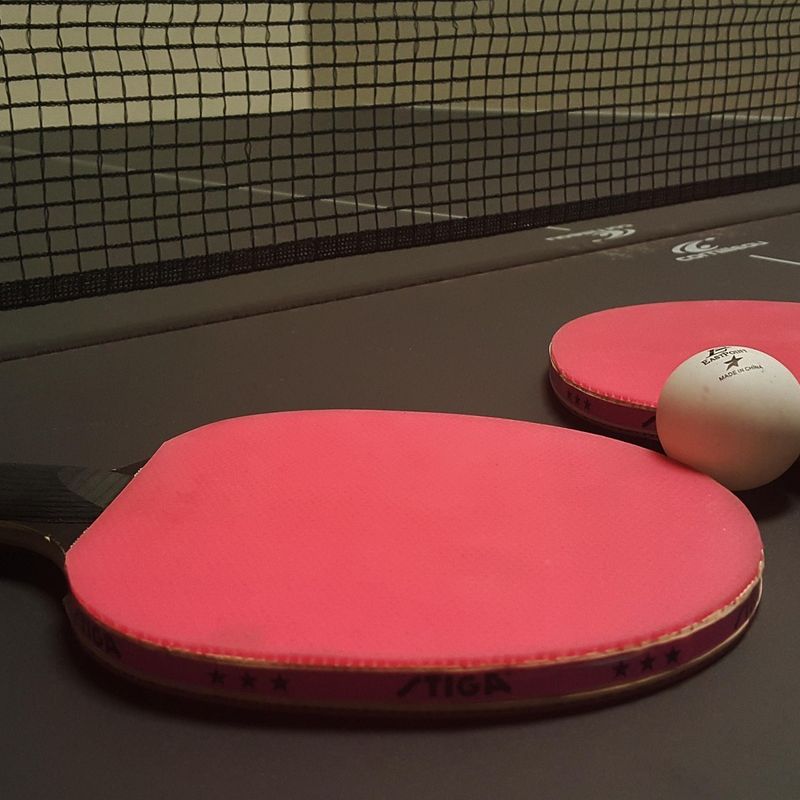 Black and red ping pong paddles on black table
