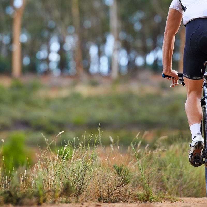 a male adult cyclist wearing padded cycling shorts riding on a dirt track
